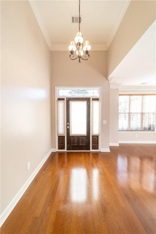 foyer featuring crown molding, a chandelier, and hardwood / wood-style flooring