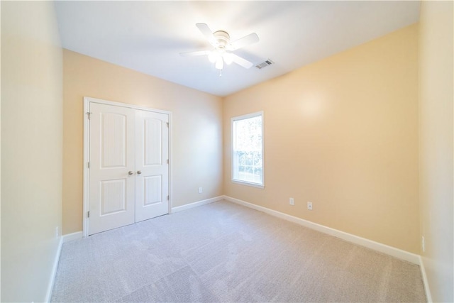 unfurnished bedroom featuring ceiling fan, a closet, and light carpet