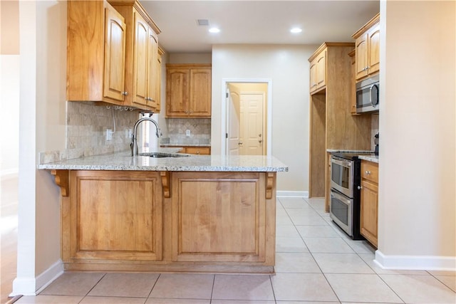 kitchen featuring light stone counters, sink, kitchen peninsula, and stainless steel appliances