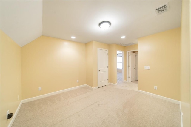 carpeted empty room with vaulted ceiling