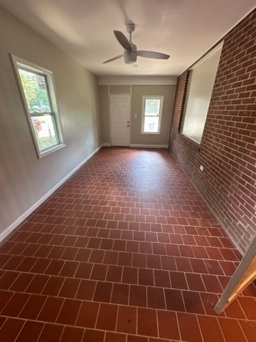 empty room with ceiling fan and brick wall