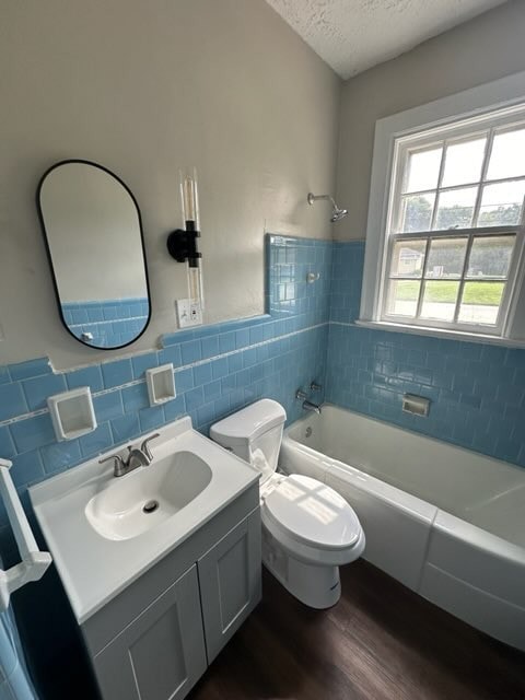 full bathroom with shower / bathtub combination, vanity, a textured ceiling, wood-type flooring, and toilet