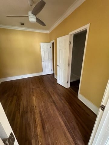 unfurnished bedroom featuring a walk in closet, ceiling fan, dark hardwood / wood-style flooring, and ornamental molding