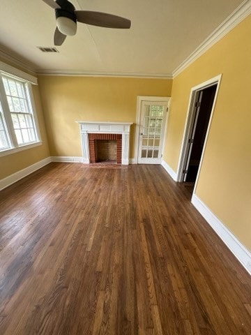 unfurnished living room featuring ceiling fan, a fireplace, dark wood-type flooring, and ornamental molding