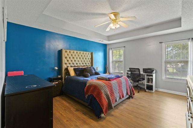 1417 Ridge Rd, Opelika, AL 36801 - bedroom featuring a tray ceiling, a textured ceiling, multiple windows, wood finished floors, and ceiling fan