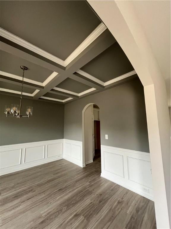 unfurnished room featuring dark wood-style floors, arched walkways, coffered ceiling, and a chandelier