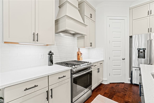 kitchen featuring light stone counters, stainless steel appliances, white cabinetry, dark wood finished floors, and custom range hood