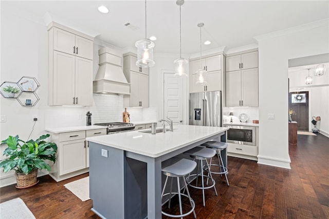 kitchen with a kitchen island with sink, stainless steel appliances, hanging light fixtures, light countertops, and custom exhaust hood