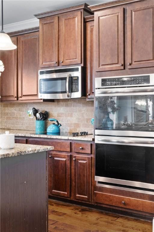 300 Holland Loop, Smiths Station, AL 36877 - kitchen featuring appliances with stainless steel finishes, crown molding, dark wood-style flooring, hanging light fixtures, and backsplash