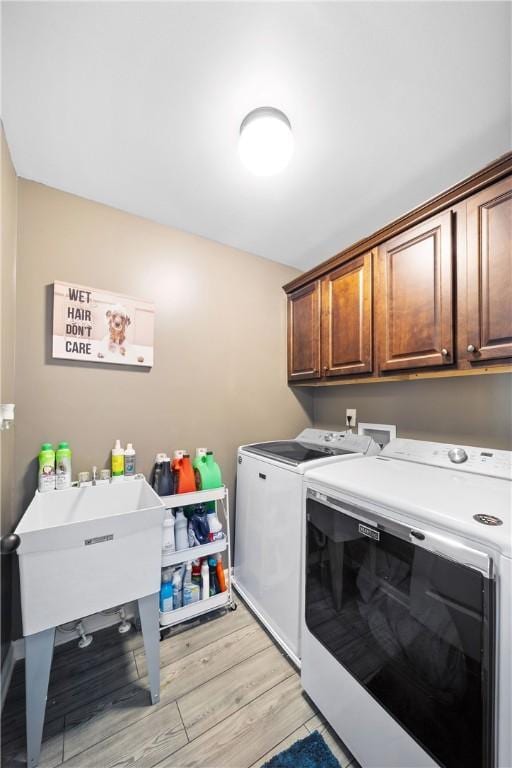 300 Holland Loop, Smiths Station, AL 36877 - washroom with washing machine and clothes dryer, cabinet space, and light wood-style flooring