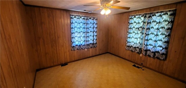 unfurnished room with ceiling fan and wood walls