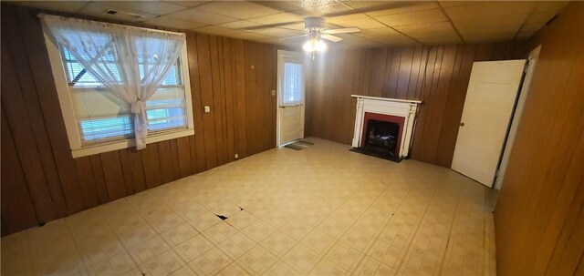 unfurnished living room featuring wooden walls and ceiling fan