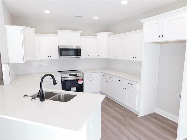 kitchen with decorative backsplash, white cabinetry, sink, and appliances with stainless steel finishes