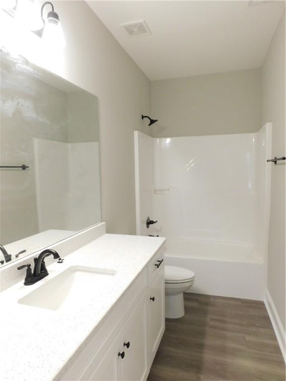 full bathroom featuring vanity, toilet, wood-type flooring, and shower / washtub combination