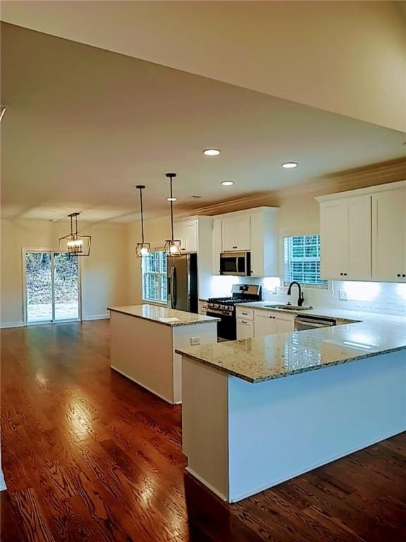 kitchen with white cabinetry, a center island, appliances with stainless steel finishes, dark hardwood / wood-style flooring, and pendant lighting