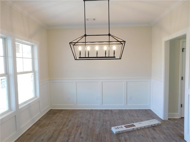 unfurnished dining area with dark wood-type flooring, crown molding, and an inviting chandelier