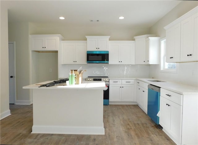 kitchen featuring white cabinets, light wood-type flooring, stainless steel appliances, and a kitchen island