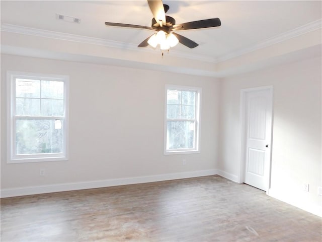 empty room featuring ceiling fan, a raised ceiling, and crown molding