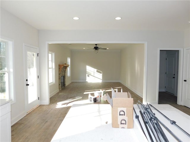 interior space with ceiling fan, light hardwood / wood-style floors, white cabinets, and a fireplace