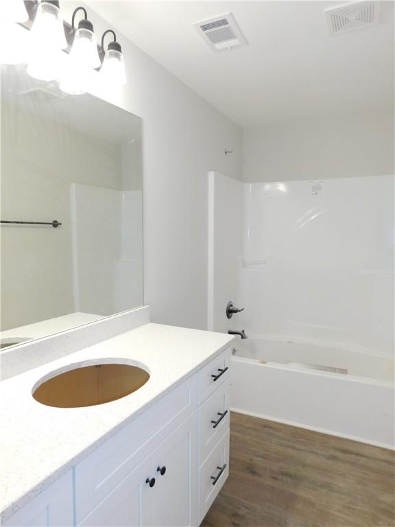 bathroom featuring wood-type flooring, washtub / shower combination, and vanity