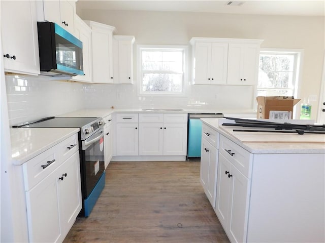 kitchen with appliances with stainless steel finishes, a healthy amount of sunlight, white cabinetry, and tasteful backsplash