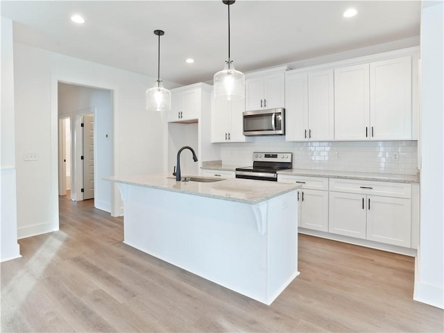 083 Bradley Ln, Auburn, AL 36830 - kitchen featuring appliances with stainless steel finishes, light wood-style floors, backsplash, a kitchen island with sink, and white cabinets