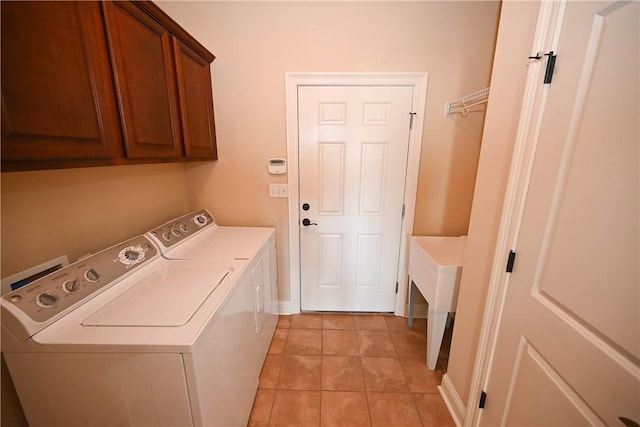 laundry room featuring washer and clothes dryer, light tile patterned floors, and cabinets