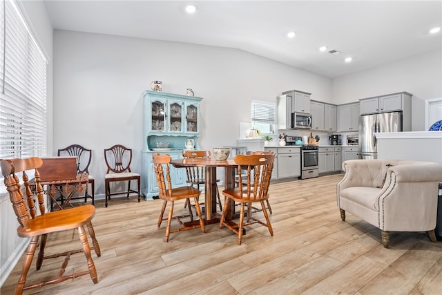 dining space featuring light hardwood / wood-style floors and vaulted ceiling