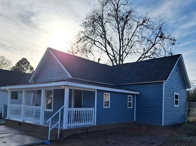 back house at dusk featuring covered porch