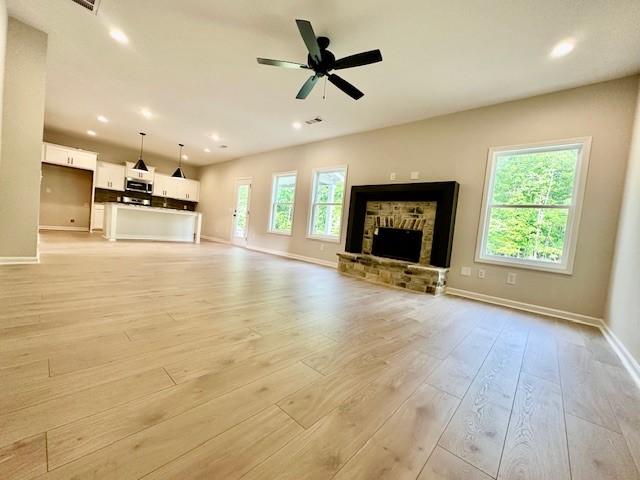 750 Mcdonald Dr, Opelika, AL 36801 - unfurnished living room featuring baseboards, light wood finished floors, recessed lighting, a ceiling fan, and a stone fireplace