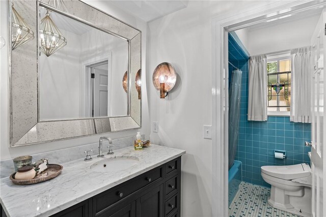 613 5th Ave, Opelika, AL 36801 - bathroom featuring tile patterned floors, toilet, vanity, shower / bath combo with shower curtain, and tile walls