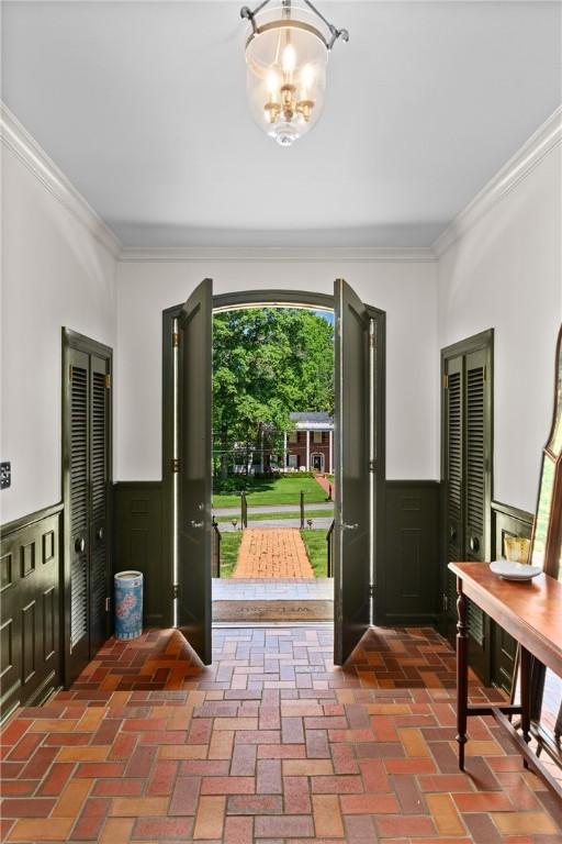 613 5th Ave, Opelika, AL 36801 - entryway with ornamental molding, a wainscoted wall, a chandelier, and brick floors
