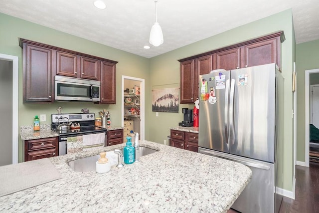 kitchen featuring light stone counters, dark wood-type flooring, baseboards, appliances with stainless steel finishes, and pendant lighting