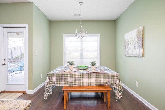 dining room with an inviting chandelier, baseboards, visible vents, and wood finished floors