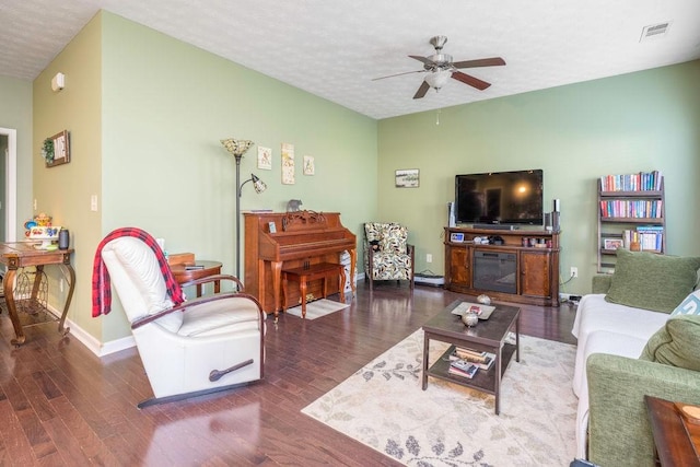 living area with a textured ceiling, dark wood-style flooring, visible vents, and baseboards