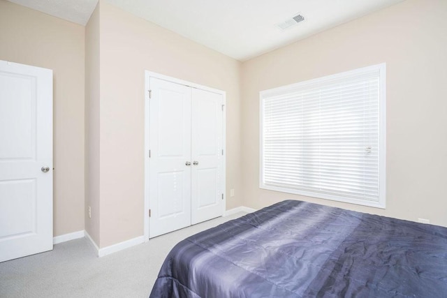 bedroom featuring a closet, carpet flooring, visible vents, and baseboards