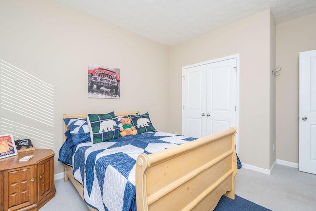 bedroom featuring a closet, light carpet, and baseboards