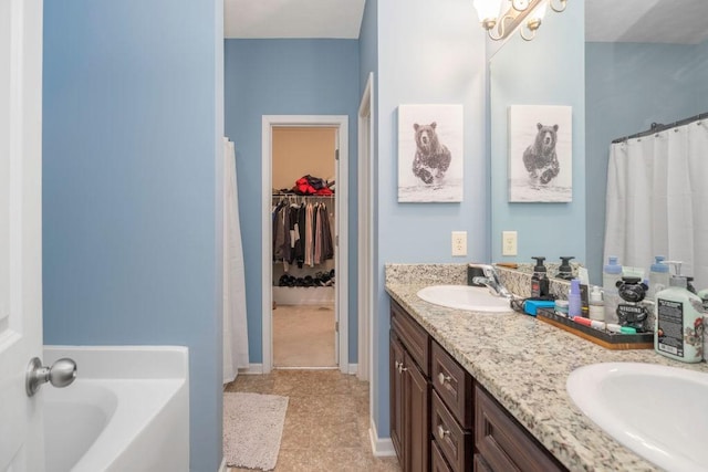 bathroom with a walk in closet, a garden tub, a sink, and double vanity