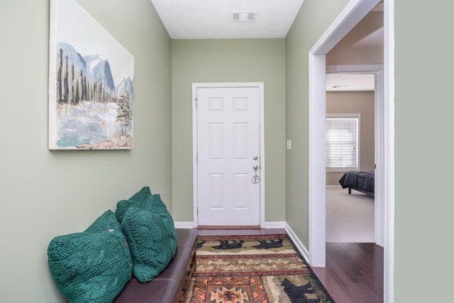 foyer with wood finished floors, visible vents, and baseboards