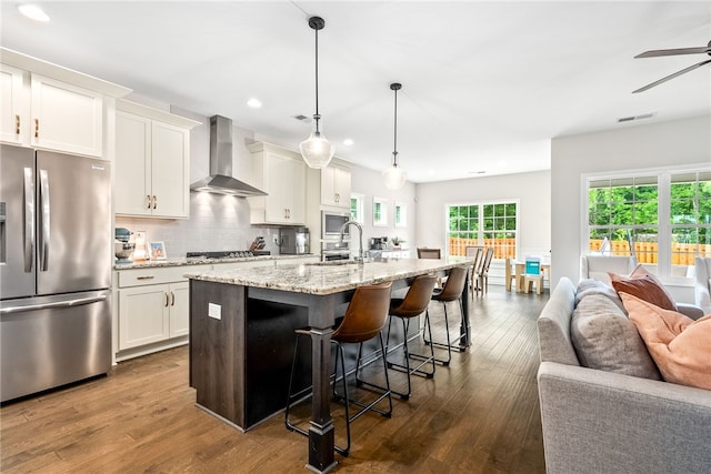 1803 Solamere Ct, Auburn, AL 36832 - kitchen featuring stainless steel appliances, wall chimney range hood, open floor plan, a breakfast bar area, and an island with sink