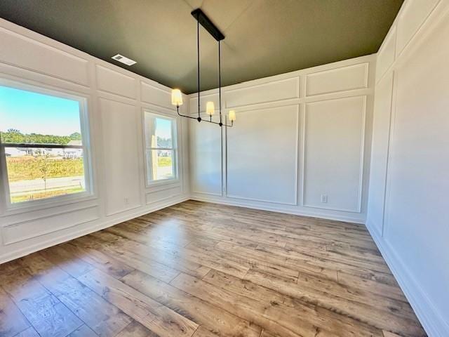 unfurnished dining area featuring light wood-type flooring and an inviting chandelier