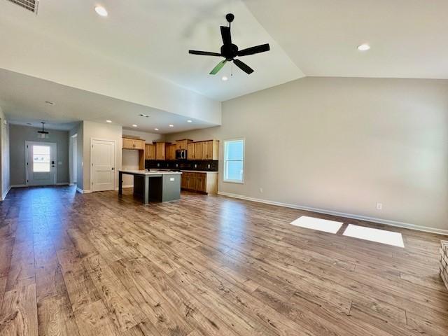 unfurnished living room with hardwood / wood-style flooring, ceiling fan, and lofted ceiling