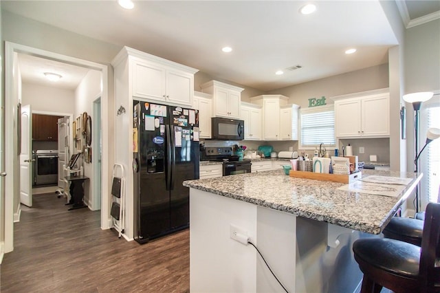 kitchen featuring a center island, dark hardwood / wood-style flooring, a kitchen bar, white cabinets, and black appliances