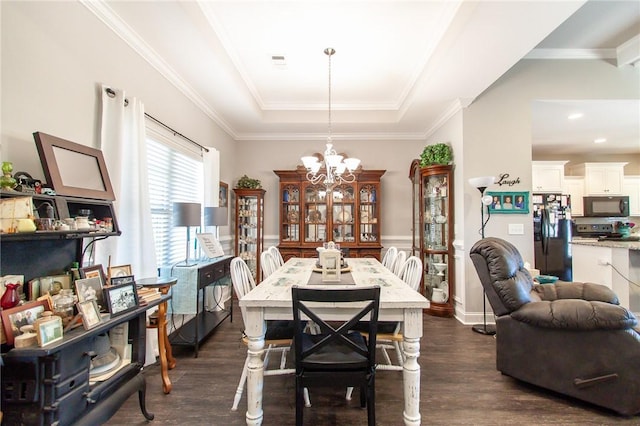 dining space with a raised ceiling, crown molding, dark wood-type flooring, and an inviting chandelier