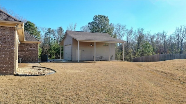 view of yard featuring a garage, ceiling fan, and central air condition unit