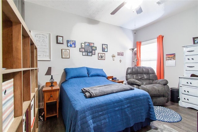 bedroom with a textured ceiling, ceiling fan, and dark hardwood / wood-style floors