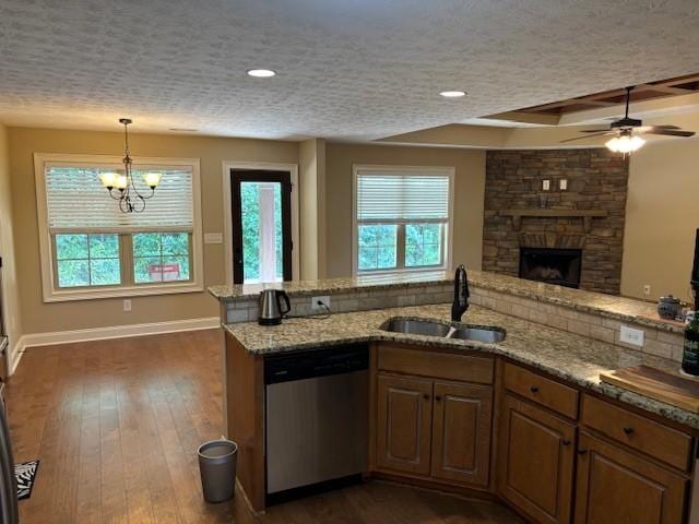 kitchen featuring plenty of natural light, dark wood-style floors, a textured ceiling, stainless steel dishwasher, and a sink