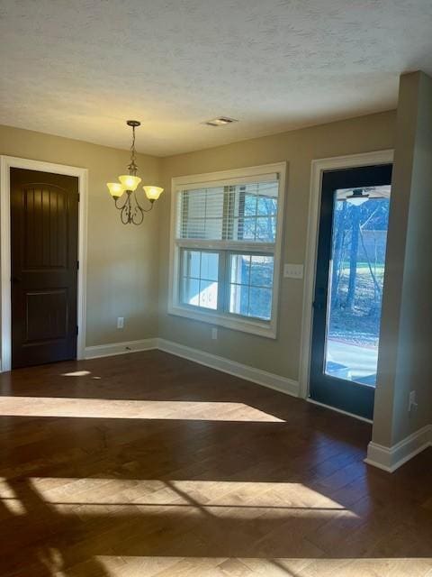 entrance foyer featuring a chandelier, a textured ceiling, baseboards, and wood finished floors