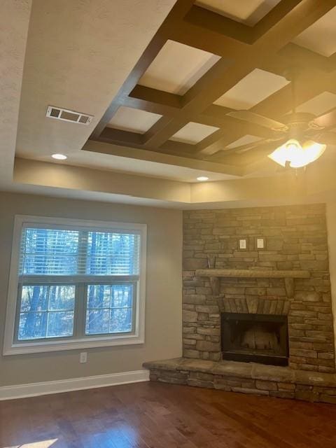 unfurnished living room featuring visible vents, a stone fireplace, wood finished floors, coffered ceiling, and baseboards