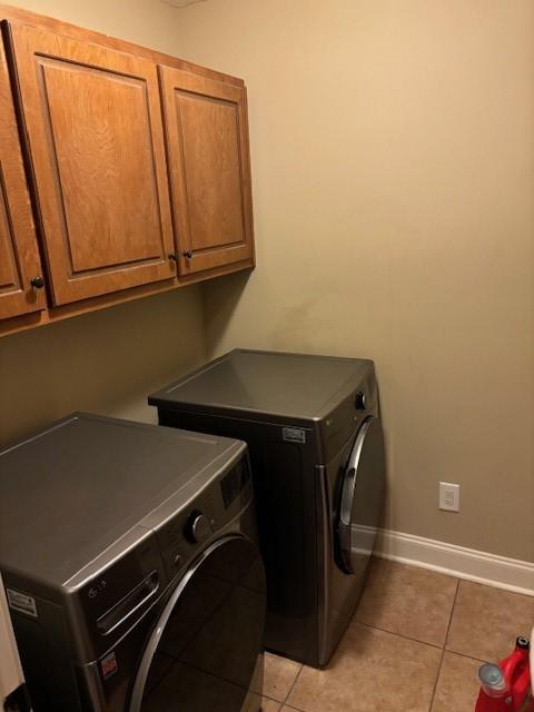 clothes washing area with cabinet space, baseboards, separate washer and dryer, and light tile patterned flooring